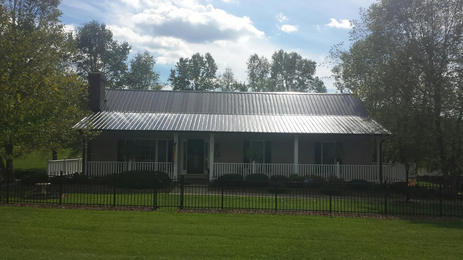 Gray metal roof on a brick ranch with a full width front porch — Gutter Guard Installation work by our crew in Pikeville